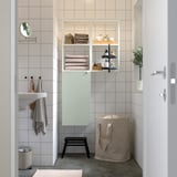 Modern bathroom with green ENHET storage, open/closed compartments, neat towels.