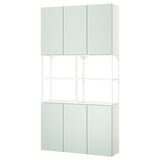 An ENHET storage combination in pale green. Its a tall unit with closed cabinets on top and bottom, and open shelves in the middle.