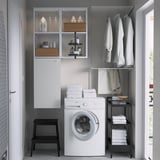 Compact laundry setup: ENHET washing machine, wall cabinet, hanging rod, shelving, step stool.