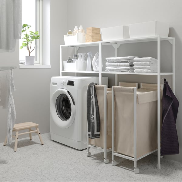 White ENHET laundry setup: washing machine, towel shelves, rolling laundry bag.