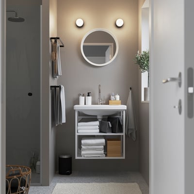 Modern bathroom: wall-mounted white sink with round mirror, minimalist style.