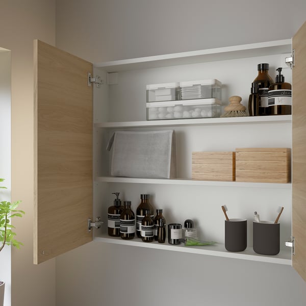 Open oak cabinet shows organized toiletries like bottles, jars, and containers, with shelves inside.