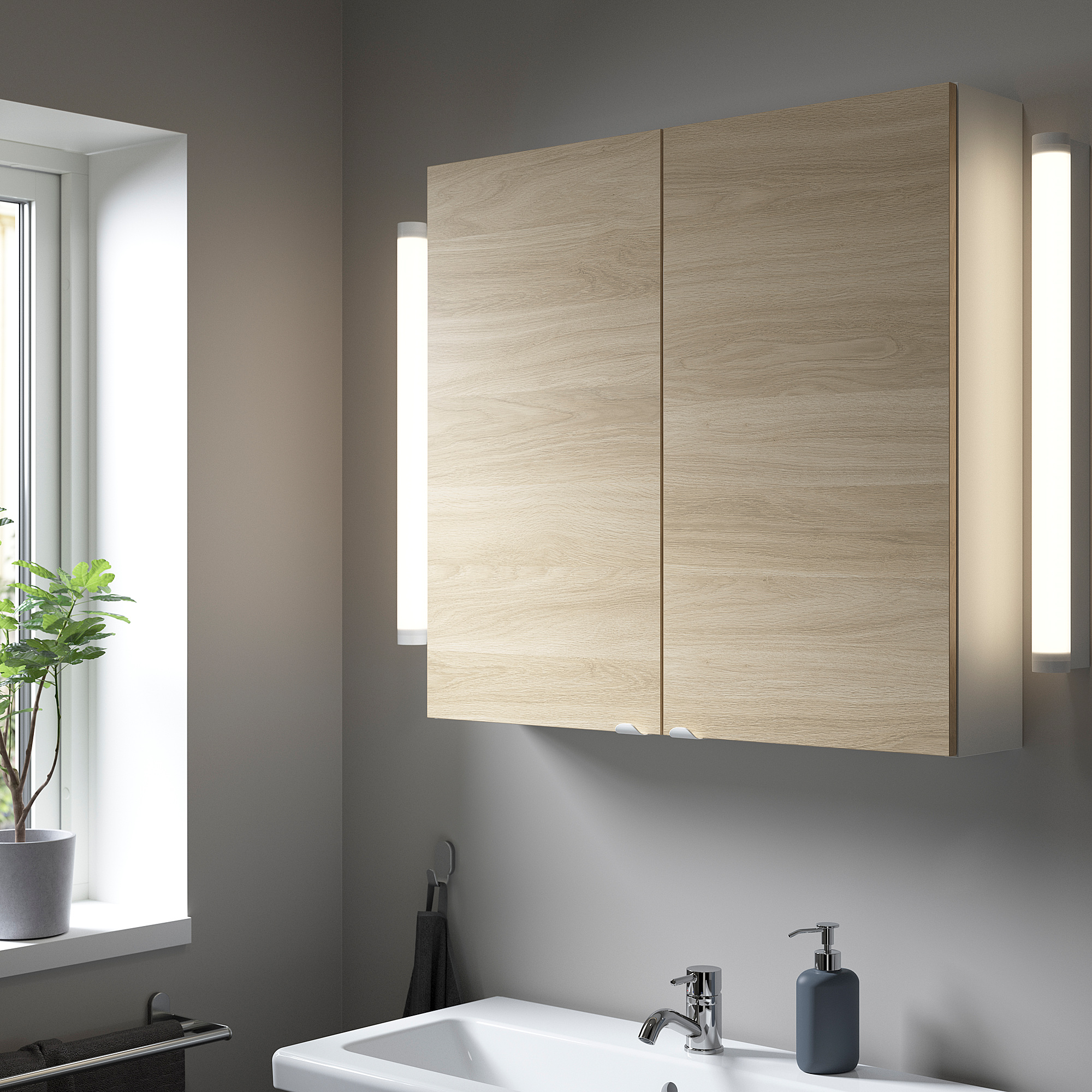 Modern bathroom with large light wood cabinet above sink, grey wall, plants by window.
