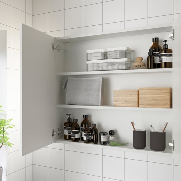 White wall cabinet with two shelves storing toiletries and organized items.
