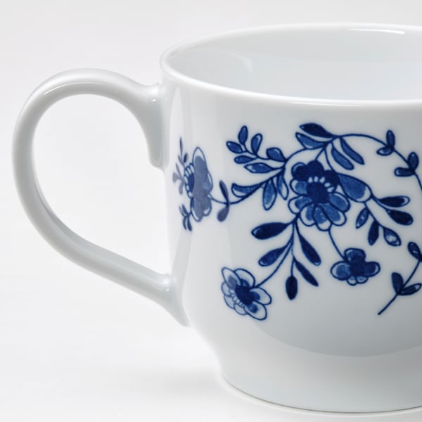 Elegant white mug with intricate blue floral design, smooth handle, and glossy finish. High-quality porcelain.