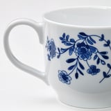 Elegant white mug with intricate blue floral design, smooth handle, and glossy finish. High-quality porcelain.