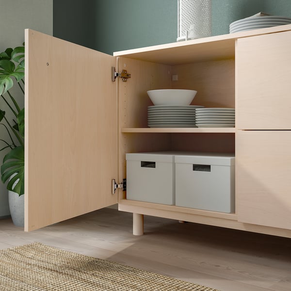 Light wooden sideboard with open door revealing plates and boxes.