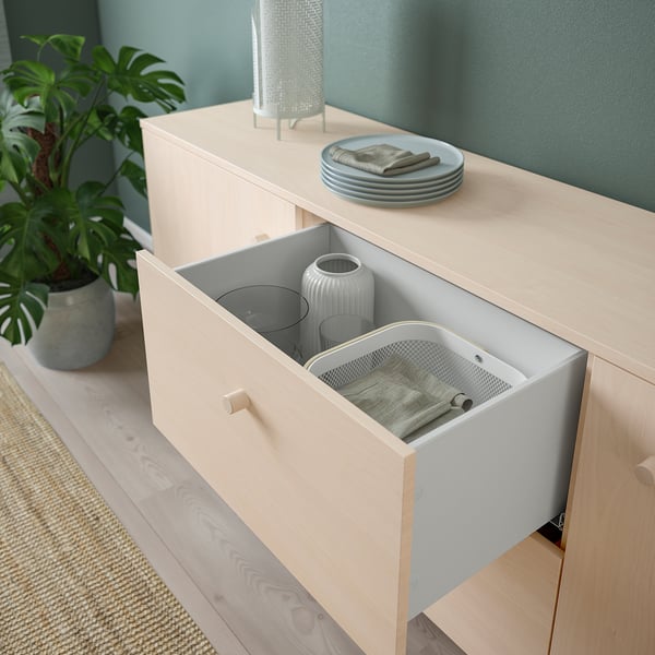 Light wood sideboard with open drawer showing vases, cloth, and lid. Modern, functional storage with a natural birch look.