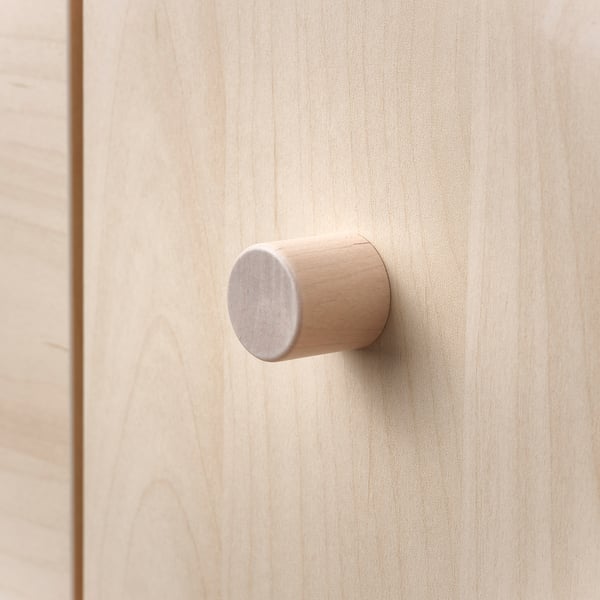 Small, cylindrical wooden knot on light wood. Modern, minimalist design.