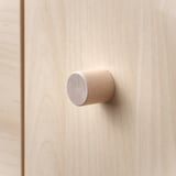 Small, cylindrical wooden knot on light wood. Modern, minimalist design.