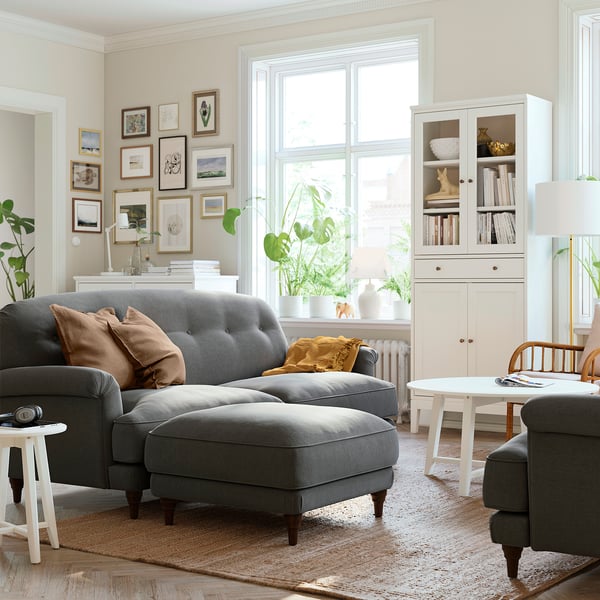 Cozy living room with ESSEBODA gray sofa, white coffee table, wall art, plants, and a bookcase.