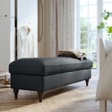 Gray upholstered storage bench with tapered legs in a bright, airy room.