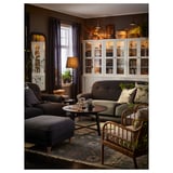 Cozy living room with ESSEBODA footstool, sofa, armchair, rug, coffee table, bookshelf, and plants.