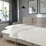 Grey FAMMARP sofa in cozy room with art, adjustable headrests, large windows, and plant.