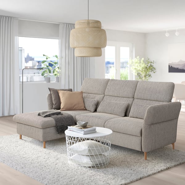 Grey FAMMARP sofa with adjustable footstool, & pillows. White coffee table, pendant light, & large windows with curtains.