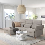 Grey FAMMARP sofa with adjustable footstool, & pillows. White coffee table, pendant light, & large windows with curtains.