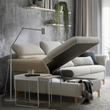 Modern gray FAMMARP sofa with adjustable headrests and backrests, wooden legs, and a small side table with a cup and remote.