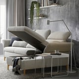 A modern, light grey FAMMARP sofa with adjustable headrests and armrests, positioned against a grey wall with floating shelves and a plant.