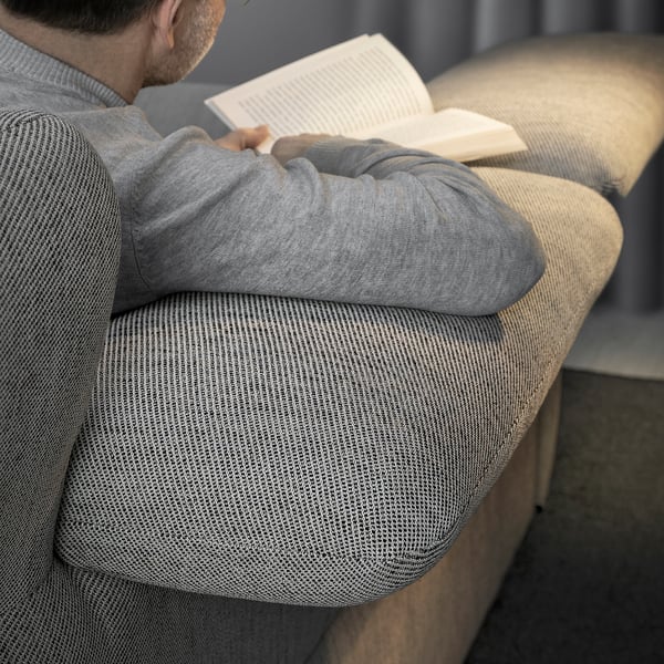 Man reading on beige FAMMARP sofa, wearing grey sweater.
