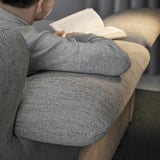 Man reading on beige FAMMARP sofa, wearing grey sweater.