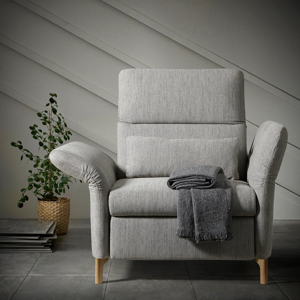 Modern, gray FAMMARP recliner with wooden legs and blanket, next to a plant.