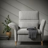 Modern, gray FAMMARP recliner with wooden legs and blanket, next to a plant.