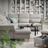 Modern living room with light gray FAMMARP sectional sofa, green pillows, black coffee table, bookshelves filled with books, plants, and cozy decor.
