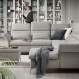 Modern living room with grey FAMMARP sofa, various cushions, and man interacting with bookshelves filled with books and decorative items.