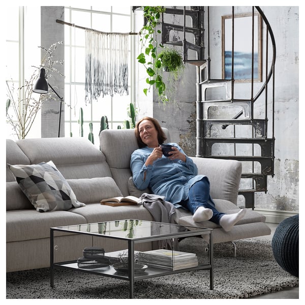 Woman on FAMMARP sofa using phone, with industrial decor.