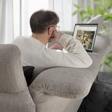 A man on a gray FAMMARP sofa, leaning back with a laptop displaying ikea.
