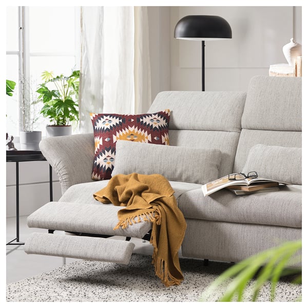 Modern grey FAMMARP sofa, patterned pillows, cozy yellow blanket, open book, stylish black lamp, plant by window.