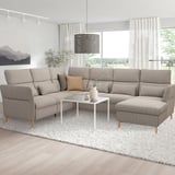 Modern living room with large l-shaped FAMMARP sofa in neutral tones, a white coffee table, and decor. Large windows and a rug.