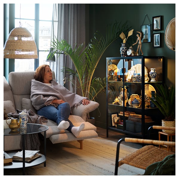 Older woman relaxing in FAMMARP sofa in cozy room with plants and decor.