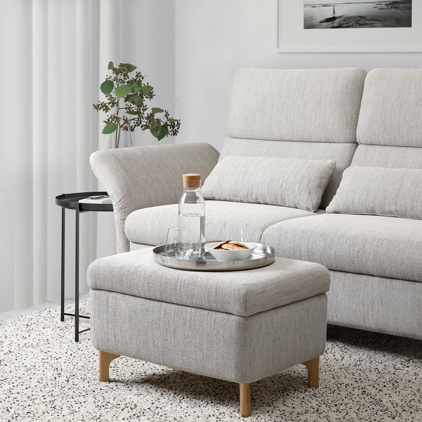 Modern living room with FAMMARP grey sofa and ottoman, side table, plant, and wall art.