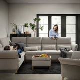 Living room with gray FAMMARP sofa, footstool, and chair. Woman with a child, windows, plants, and decorations.