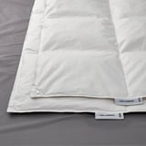 Image shows a neatly arranged white duvet on a bed, highlighting its smooth, crisp fabric and quality design.