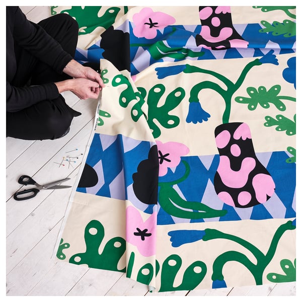 Person works on colorful fabric craft, scissors, pins nearby.