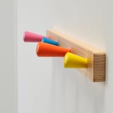 Four colorful hooks on wooden board.