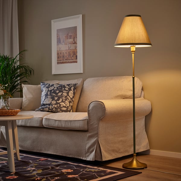 Living room with beige sofa, brass lamp, dried flowers, and artwork.
