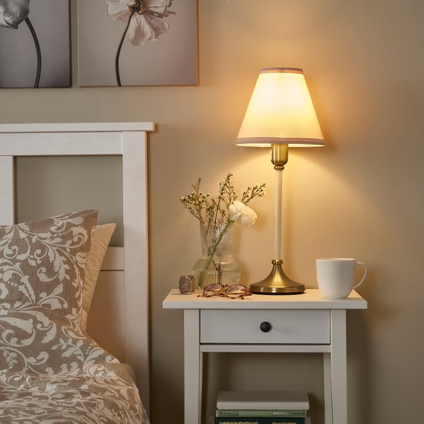 Cozy bedroom with FLYGHÖJD lamp, fresh flowers, and a patterned bed.