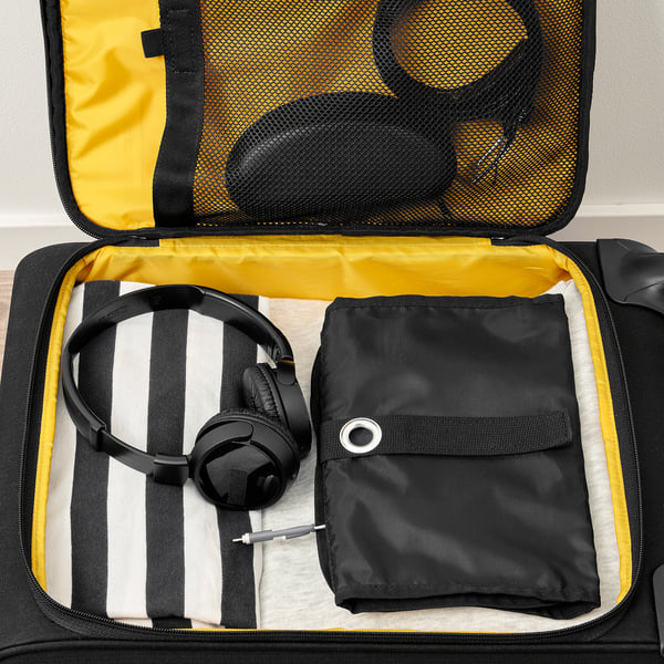 Suitcase open with headphones, a pouch, and a striped cloth tucked inside, showcasing travel organization.