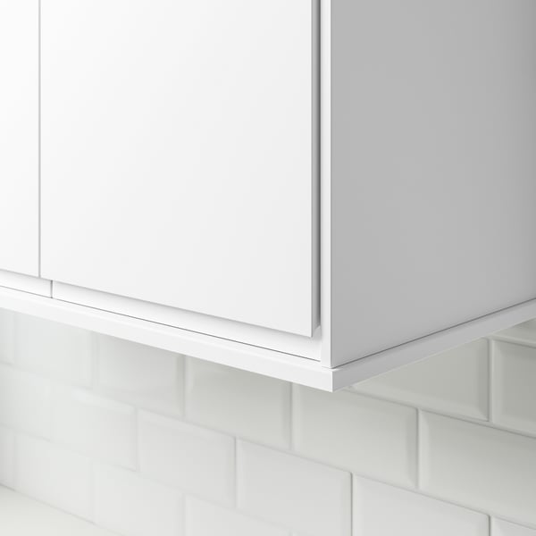 White cabinet corner with tiled wall hiding lighting.