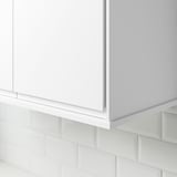 White cabinet corner with tiled wall hiding lighting.