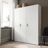 White wardrobe with two doors, placed against wall under window, with two woven baskets on top.