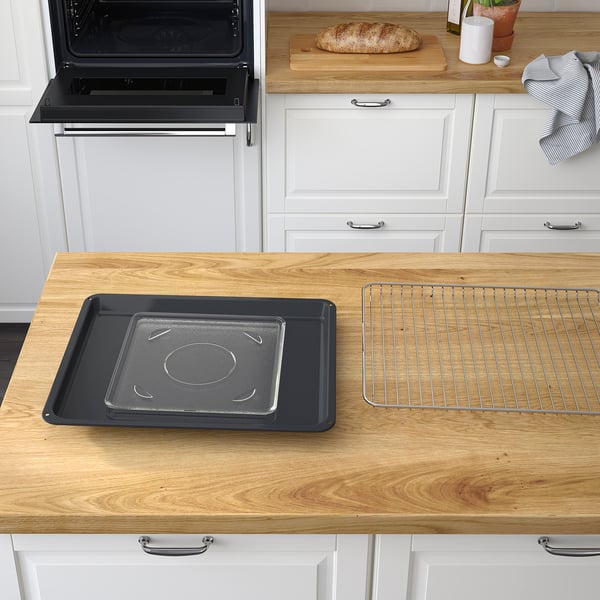 Wooden kitchen counter with an open oven door and a black baking tray on a wire rack.