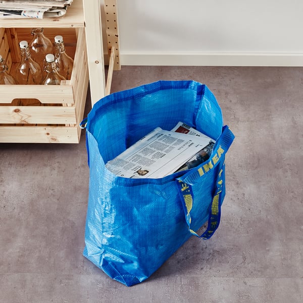 Blue ikea FRAKTA bag on floor, holding papers.