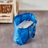 Blue ikea FRAKTA bag on floor, holding papers.