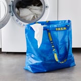 Ikea blue FRAKTA bag beside white washing machine.