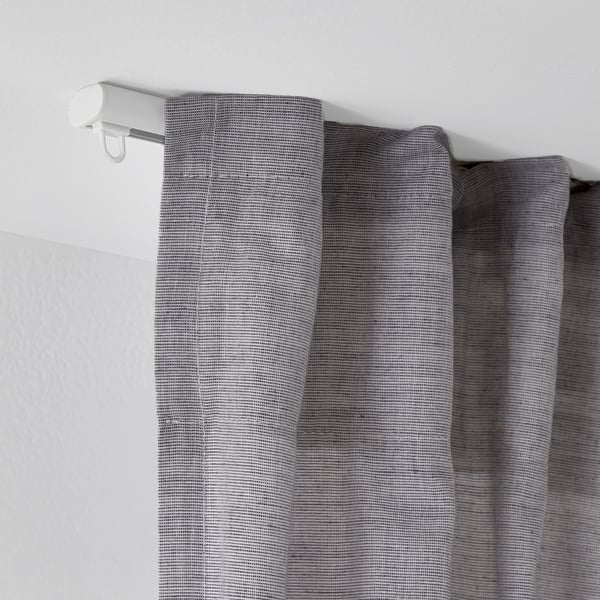 White ceiling-mounted curtain rail with gray textured curtains, showcasing FRAMFUSIGs adjustable rail system.