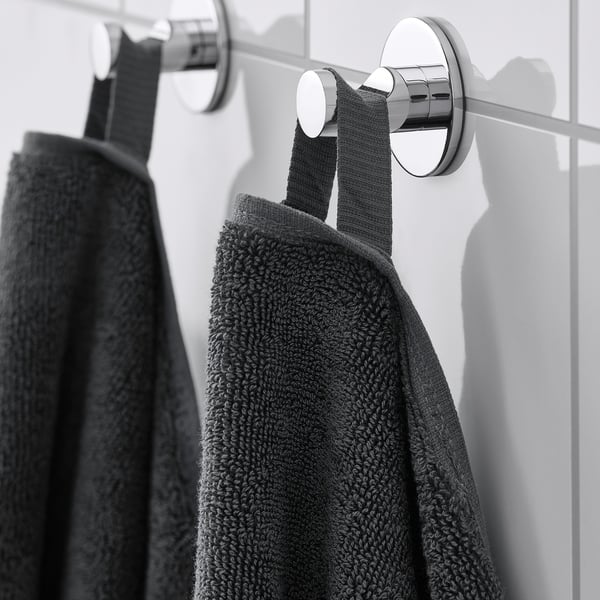 Dark towels hang on wall-mounted hooks. Sleek chrome hooks securely hold thick towels, showcasing their absorbent and decorative design.